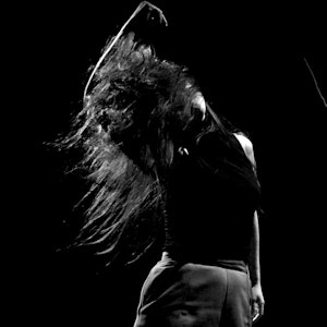 Kvinne som danser med håret til alle kanter, i svart-hvitt.