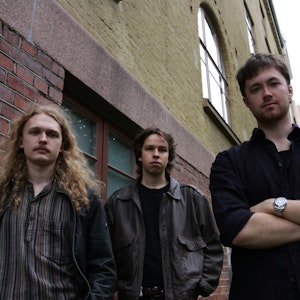 Musikerne i bandet Kjeltring står foran murbygg.