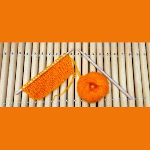 Orange strikketøy ligger oppå et melodisk slagverksinstrument.