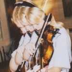 Jente med headset på hodet spiller på en fiolin. Bildet er redigert slik at det ser ut som om jenta gjentar seg som et ekko.