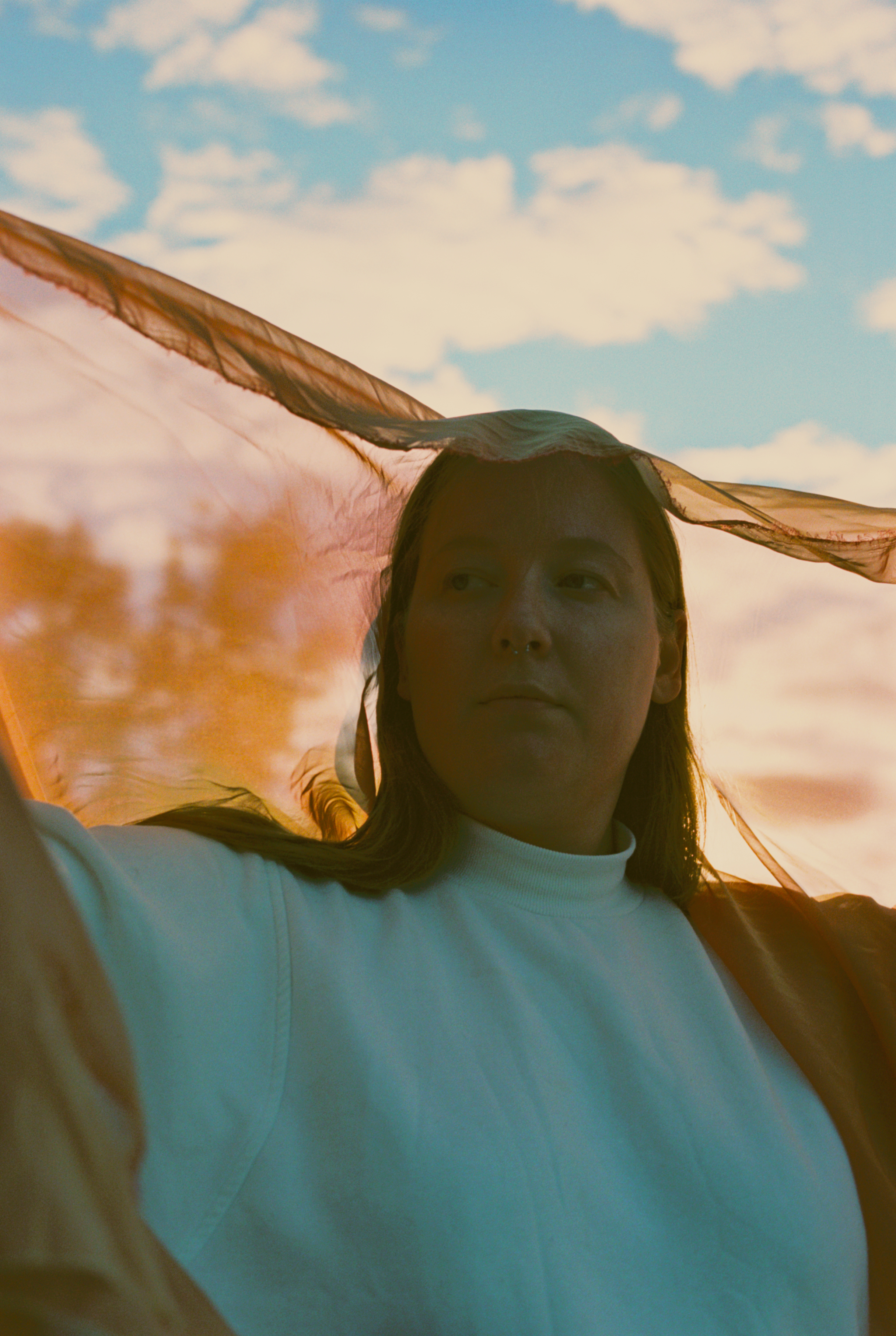 Kaurin står under en blå, skyflekket himeml med et gjennomsiktig slør på hodet.