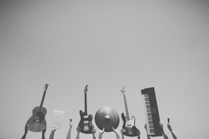 En gitar, en laptop, to mikrofoner, en el-gitar, en el-bass, en cymbal og et keyboard er løftet opp i været.