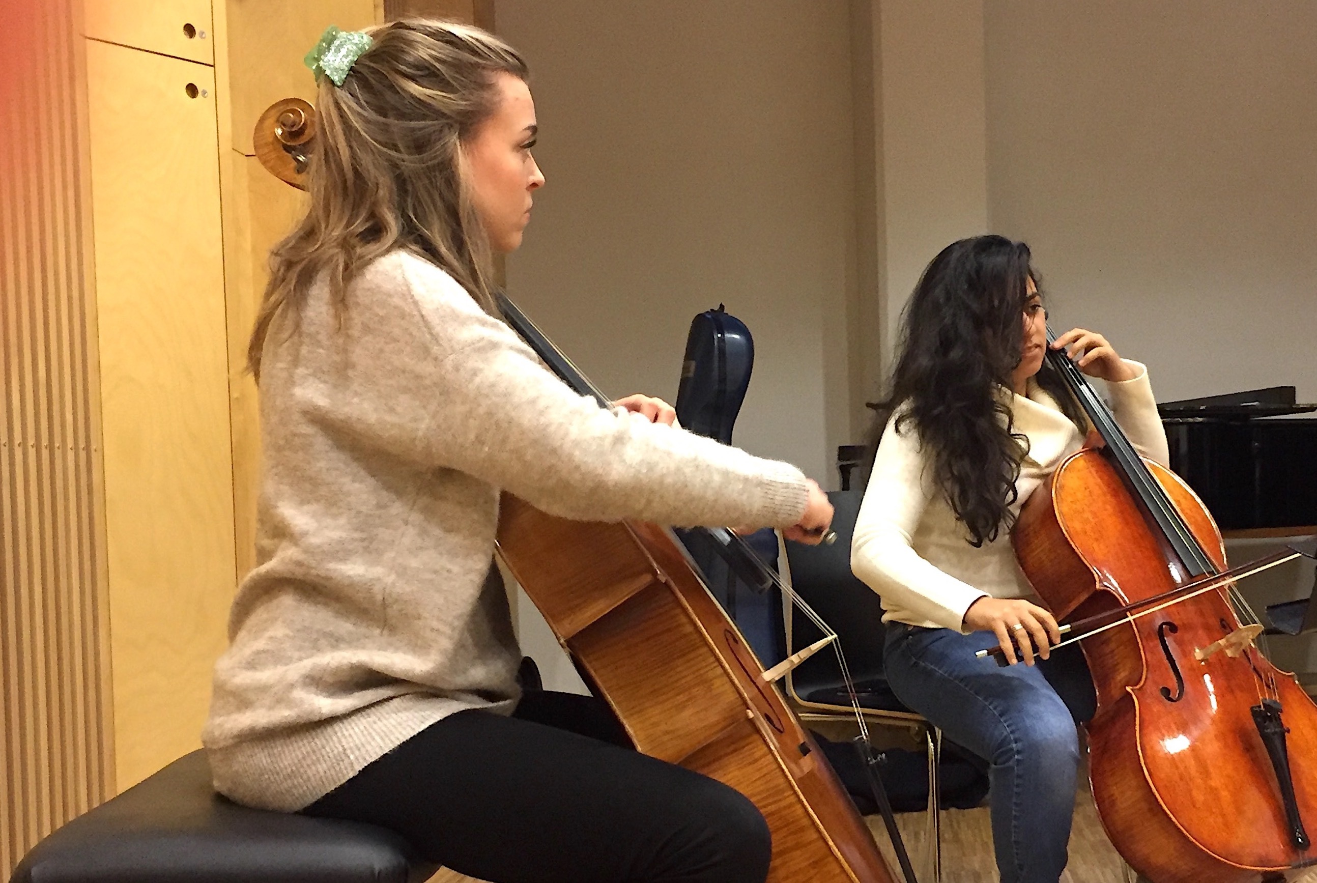 To stundenter sitter i et rom og spiller cello.
