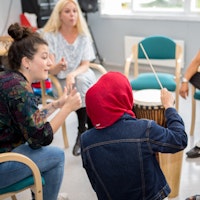 En student sitter i en lyttering og viser hvordan de fem andre skal spille på instrumentene sine.