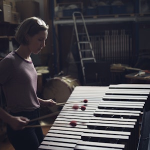 En jente står konsentrert og spiller vibrafon med to køller i hver hånd.