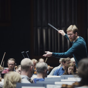 En mann dirigerer et orkester med stor innlevelse.