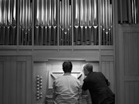 En student spiller på orgelet i Levinsalen. Læreren står ved siden av og peker på notearket.