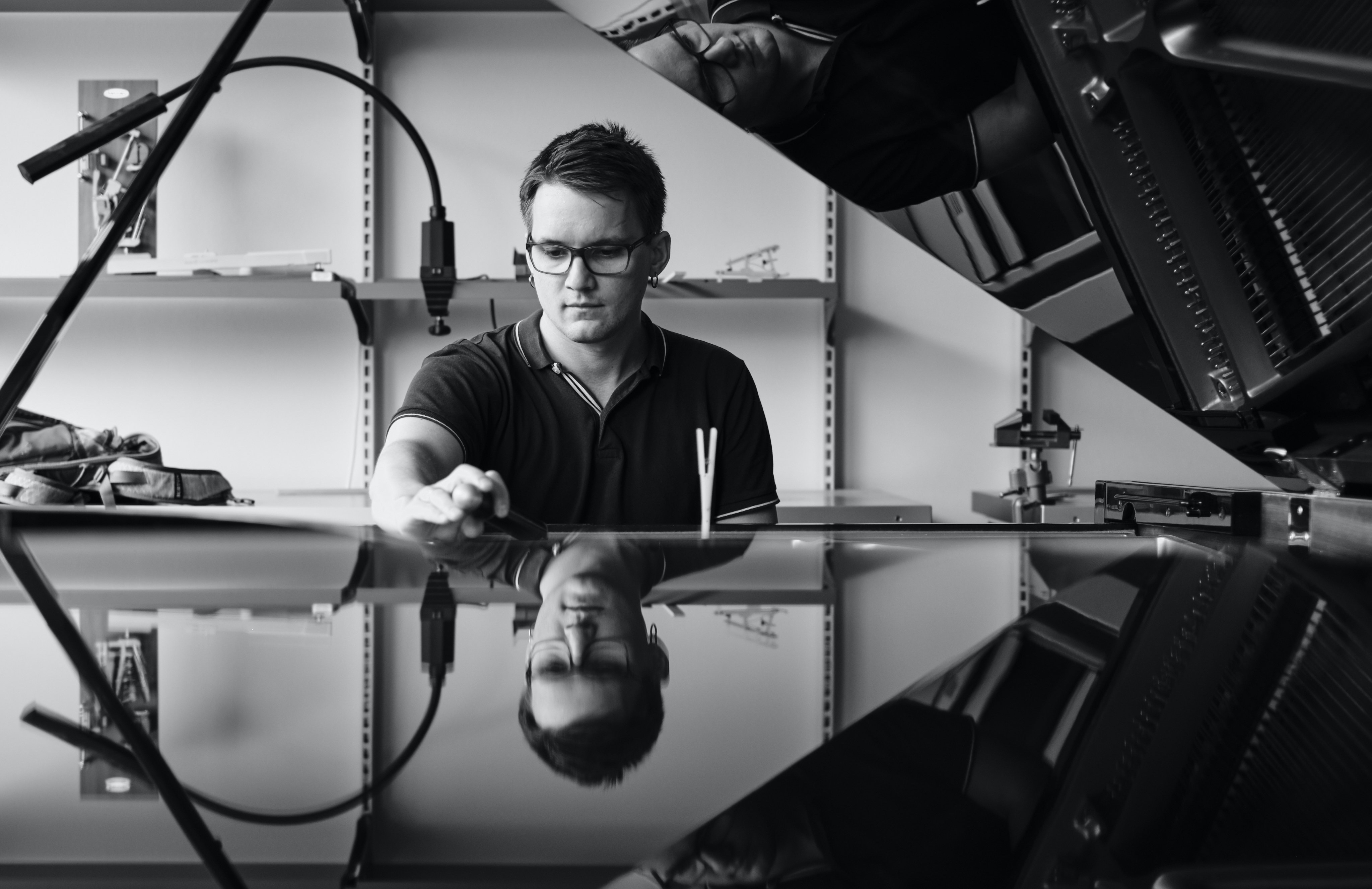 Torkil is sitting behind a grand piano and writing music.