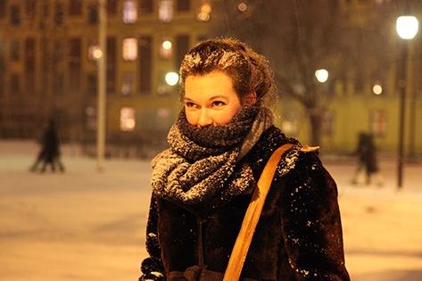 Liv Kristin står ute i skumringen. Bakken er dekket av snø, noe håret og skjerfet til Liv Kristin også er.