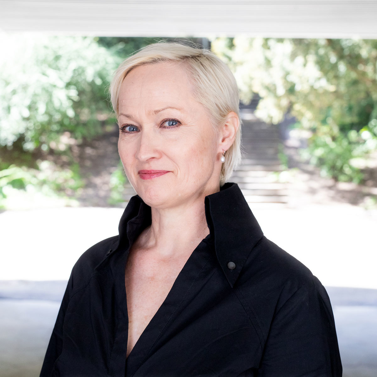 Portrett av Live Maria Roggen som står foran en hage.